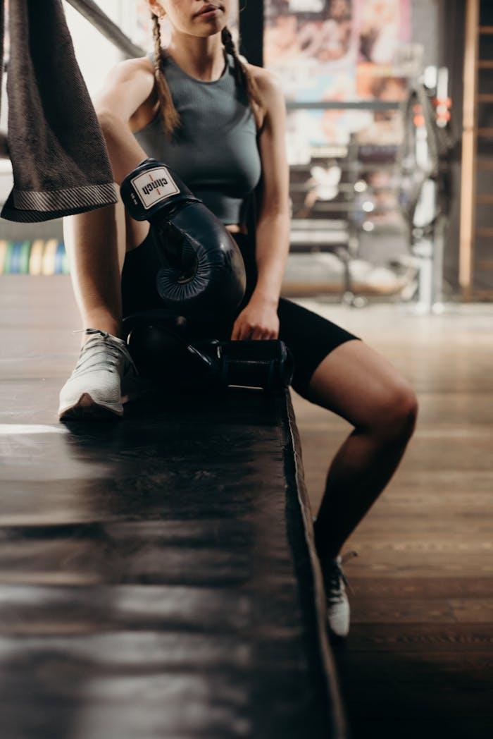 Mastering the First Impression: Your intriguing post title goes here Young woman boxer resting on boxing ring edge in a gym setting.